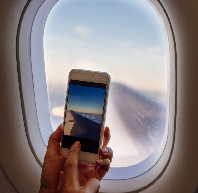 close-up-woman-hands-taking-photo-plane-travel-concept (1)
