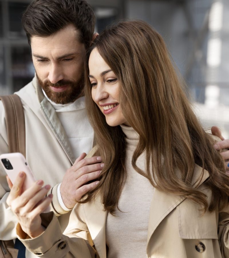 medium-shot-couple-looking-phone (1)